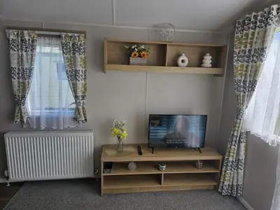 a living room with a flat screen tv and a table at Highfield Grange Holiday Park in Clacton-on-Sea