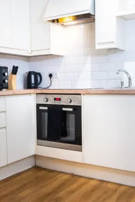 a kitchen with white cabinets and a black oven at Cozy 4-guest Getaway In The Heart Of Ipswich in Ipswich