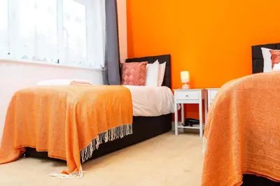 a bedroom with two beds with orange walls at Cozy 4-guest Getaway In The Heart Of Ipswich in Ipswich