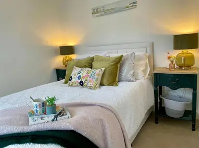 a bedroom with a white bed with pillows and a table at Stunning Beachfront House in Felixstowe