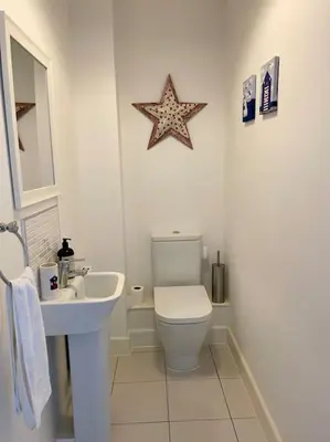 a white bathroom with a toilet and a sink at Stunning Beachfront House in Felixstowe