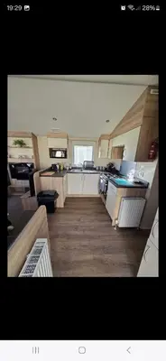 a large kitchen with wooden floors and a counter top at 8 berth caravan Martello Beach Clacton in Jaywick Sands