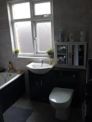 a bathroom with a sink and a toilet and a window at medium sized room in my bungalow in Great Clacton