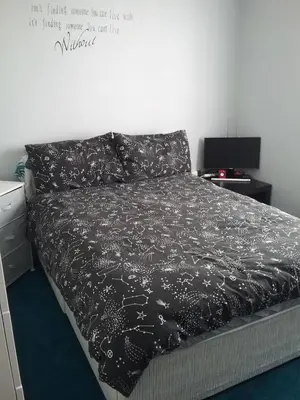 a bedroom with a bed with a black comforter at medium sized room in my bungalow in Great Clacton