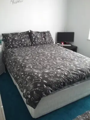a bedroom with a bed with a black comforter at medium sized room in my bungalow in Great Clacton