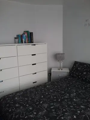a bedroom with a white dresser and a black bed at medium sized room in my bungalow in Great Clacton