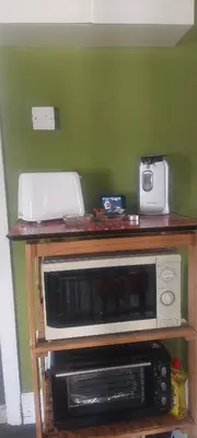 a microwave on a wooden stand with a toaster oven at Felixstowe room lets in Felixstowe