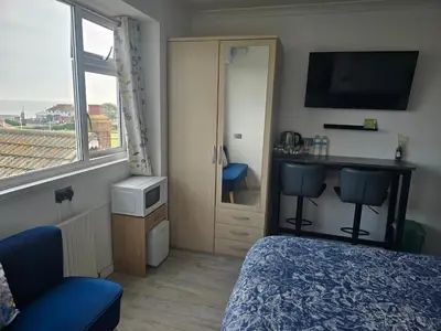 a bedroom with a bed and a desk and a window at Martello Bay Hotel in Clacton-on-Sea
