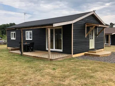 a black tiny house with a wooden deck at Nightjar Lodge - Adults Only in Lackford