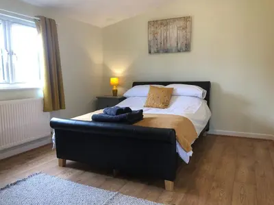 a bedroom with a large bed with a black foot board at Nightingale Lodge - Adults Only in Lackford