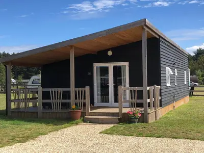 a small black house with a porch and a porch at Nightingale Lodge - Adults Only in Lackford