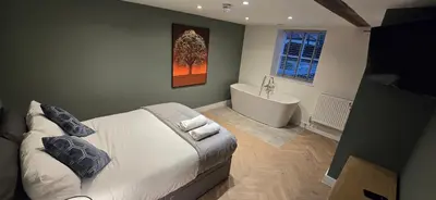 a bedroom with a large bed and a bath tub at The Greyhound Pub in Tibenham