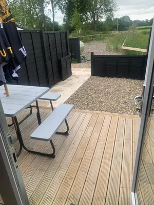 a patio with a table and a bench on a deck at The Greyhound Pub in Tibenham