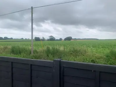 an open field with a fence and a telephone pole at The Greyhound Pub in Tibenham