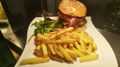 a white plate with a hamburger and french fries at The Greyhound Pub in Tibenham
