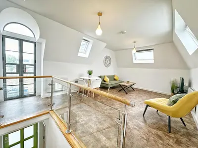 an attic living room with a staircase and yellow chairs at Gwydir Street Stays in Cambridge