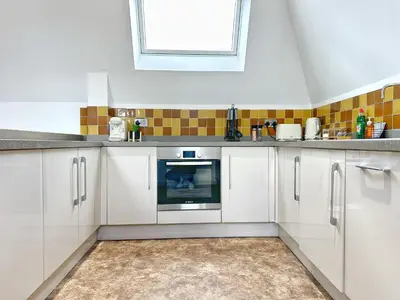 a kitchen with white cabinets and a window at Gwydir Street Stays in Cambridge