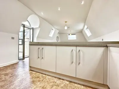 a kitchen with white cabinets and a vaulted ceiling at Gwydir Street Stays in Cambridge