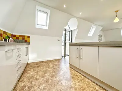 an attic kitchen with white cabinets and windows at Gwydir Street Stays in Cambridge