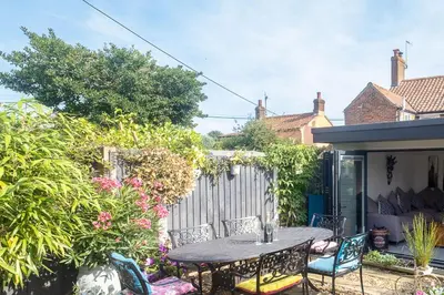 a patio with a table and chairs and a fence at 5 Burrells Cottages in Leiston