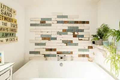 a bath tub in a bathroom with a brick wall at 5 Burrells Cottages in Leiston