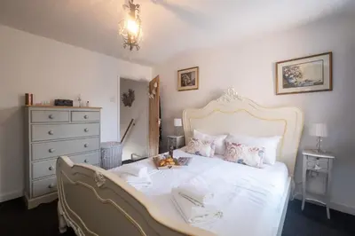 a bedroom with a white bed and a dresser at 5 Burrells Cottages in Leiston