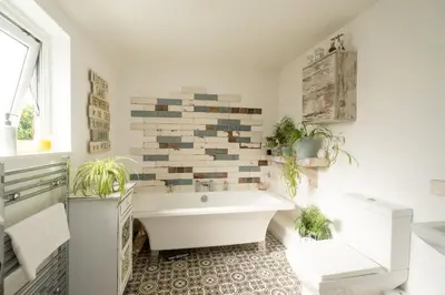 a bathroom with a white tub and plants in it at 5 Burrells Cottages in Leiston