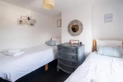 a bedroom with two beds and a dresser with a mirror at 5 Burrells Cottages in Leiston