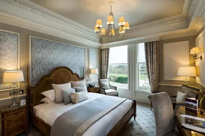 a bedroom with a large bed and a chandelier at Down Hall Hotel in Bishops Stortford