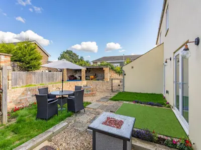 a garden with a table and chairs and an umbrella at Cathedral View Farmhouse in Ely
