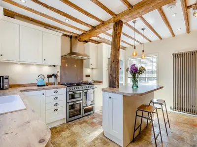 a kitchen with white cabinets and a counter with stools at Cathedral View Farmhouse in Ely
