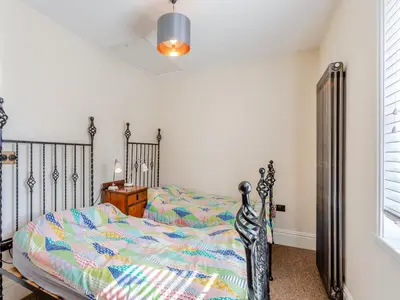 a bedroom with a bed and a dresser and a window at Cathedral View Farmhouse in Ely
