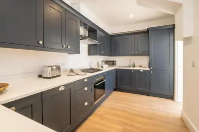 a kitchen with black cabinets and a wooden floor at Volunteer Lodge, Leiston - Aldeburgh Coastal Cottages in Leiston