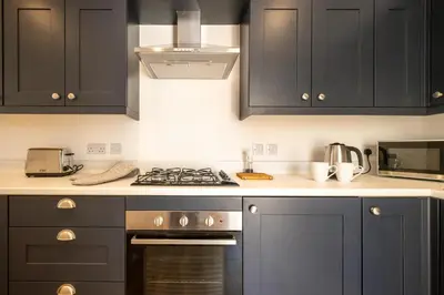 a kitchen with black cabinets and a stove top oven at Volunteer Lodge, Leiston - Aldeburgh Coastal Cottages in Leiston