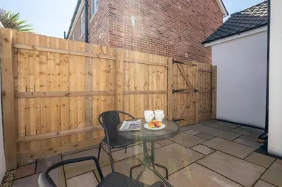a patio with a table and chairs and a fence at Volunteer Lodge, Leiston - Aldeburgh Coastal Cottages in Leiston