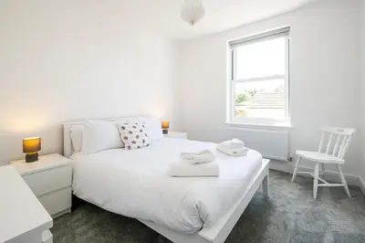 a white bedroom with a white bed and a chair at Volunteer Lodge, Leiston - Aldeburgh Coastal Cottages in Leiston