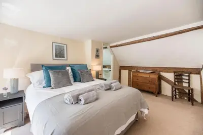 a bedroom with a large bed with blue pillows at Anchor Cottage, Orford in Woodbridge