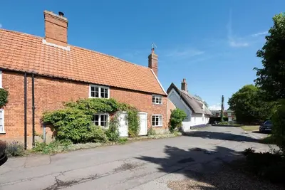 an old brick house with a street in front of it at Anchor Cottage, Orford in Woodbridge
