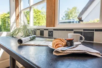 a table with a plate of bread and a cup of coffee at Anchor Cottage, Orford in Woodbridge