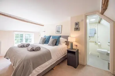 a bedroom with a large bed and a bathroom at Anchor Cottage, Orford in Woodbridge