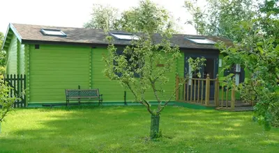 a green house with a bench in the yard at Orchard View in Bungay