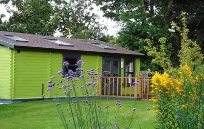 a green house with a fence in a yard at Orchard View in Bungay