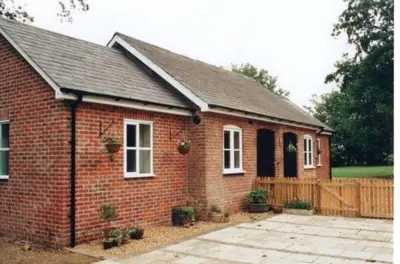 a red brick house with a wooden fence at Sam's Stable in Bungay