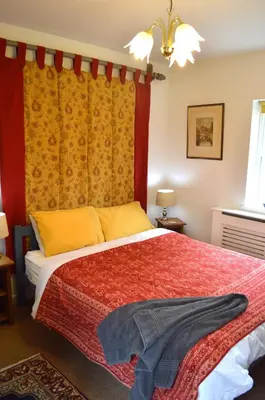 a bedroom with a red bed with a red curtain at Sam's Stable in Bungay