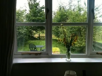 a window with a vase of flowers and a bench outside at Sam's Stable in Bungay