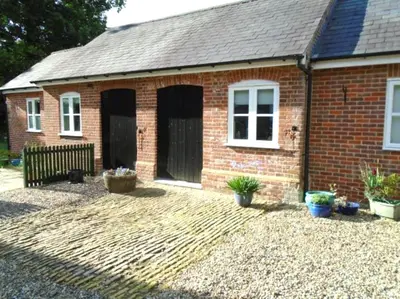 a red brick house with a courtyard in front of it at Sam's Stable in Bungay