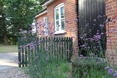 a fence with purple flowers in front of a house at Sam's Stable in Bungay