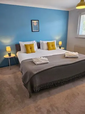 a bedroom with a large bed with a blue wall at Beautiful Aldeburgh Coastal Getaway in Aldeburgh