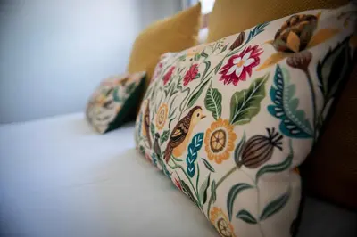 a pillow with flowers and butterflies on a couch at Pheasants Rest in Bar Hill