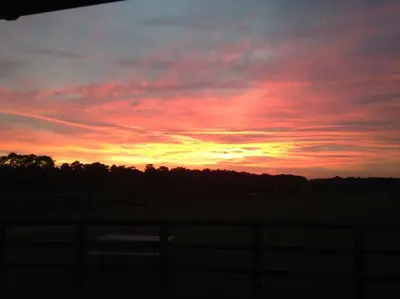 a sunset in a field with a fence at Barn Owl Lodge with Hot Tub - Adults Only in Lackford